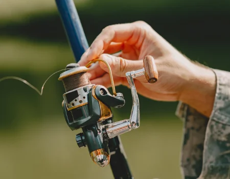 Mão manuseando um molinete em uma vara de pesca